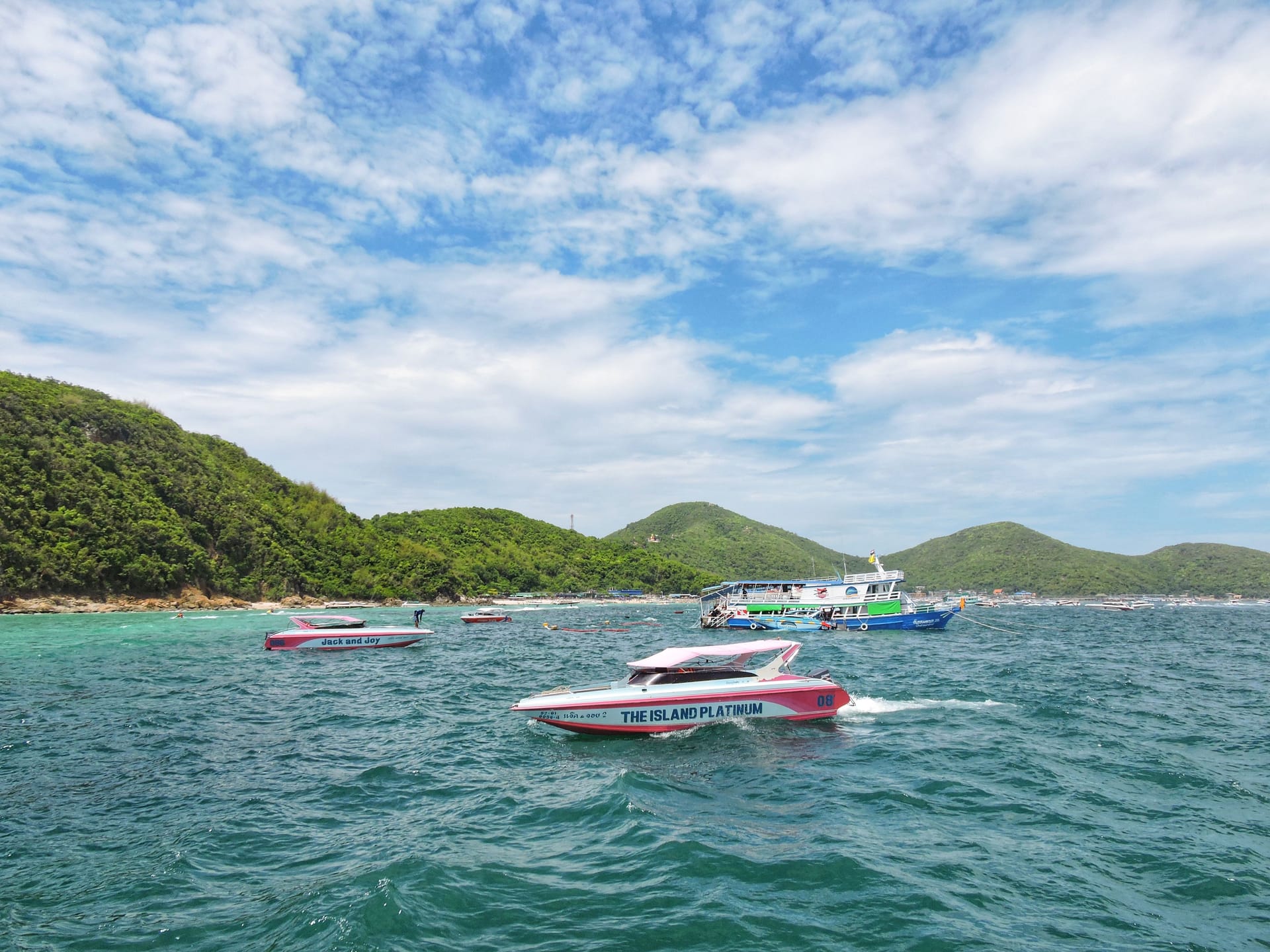 Colorful speedboats approaching a lush green island in the Gulf of Thailand, eastern seaboard, Thailand
