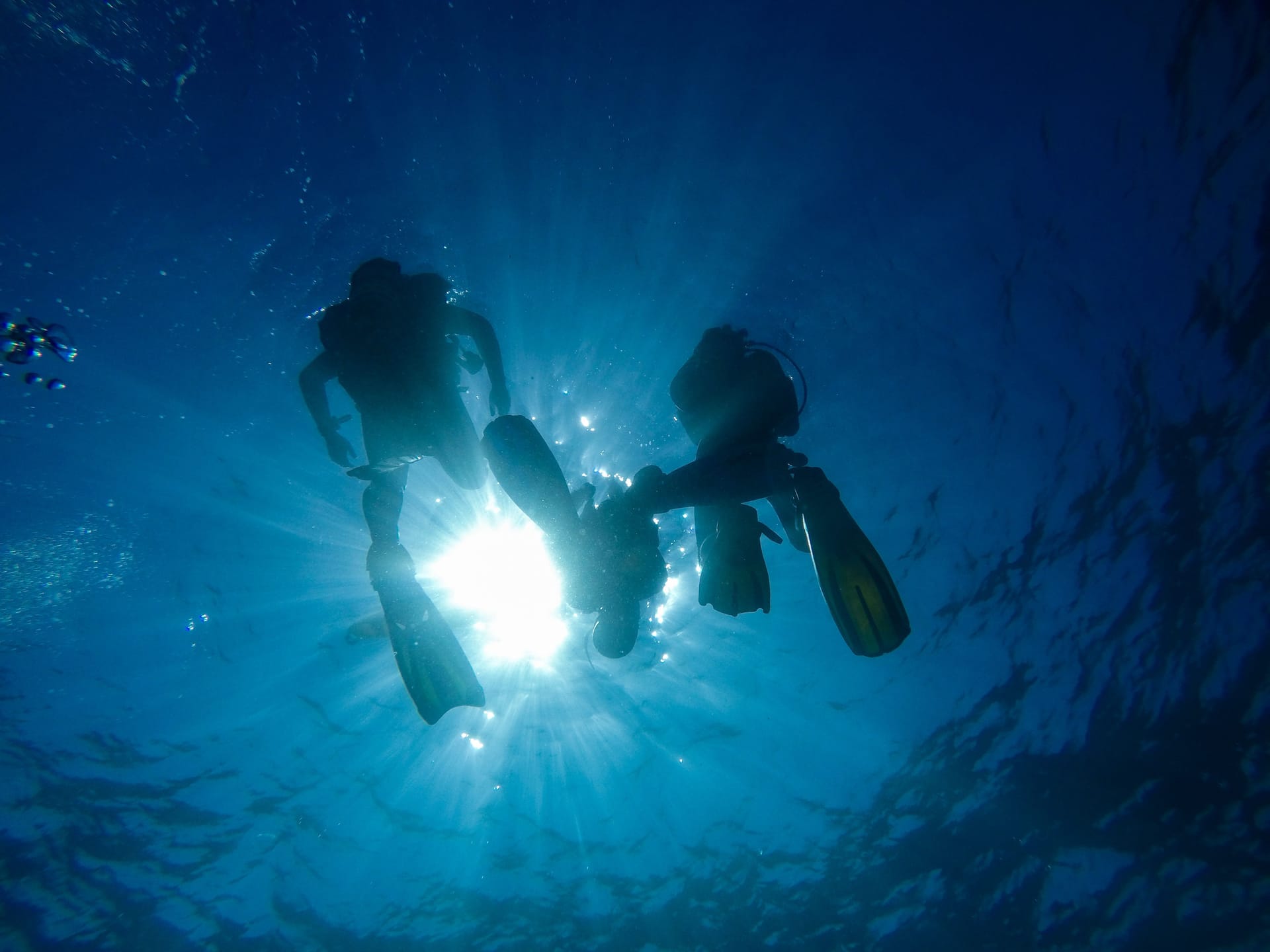 Two scuba divers silhouetted against bright sunburst in crystal-clear water, Koh Tao, Surat Thani, Thailand