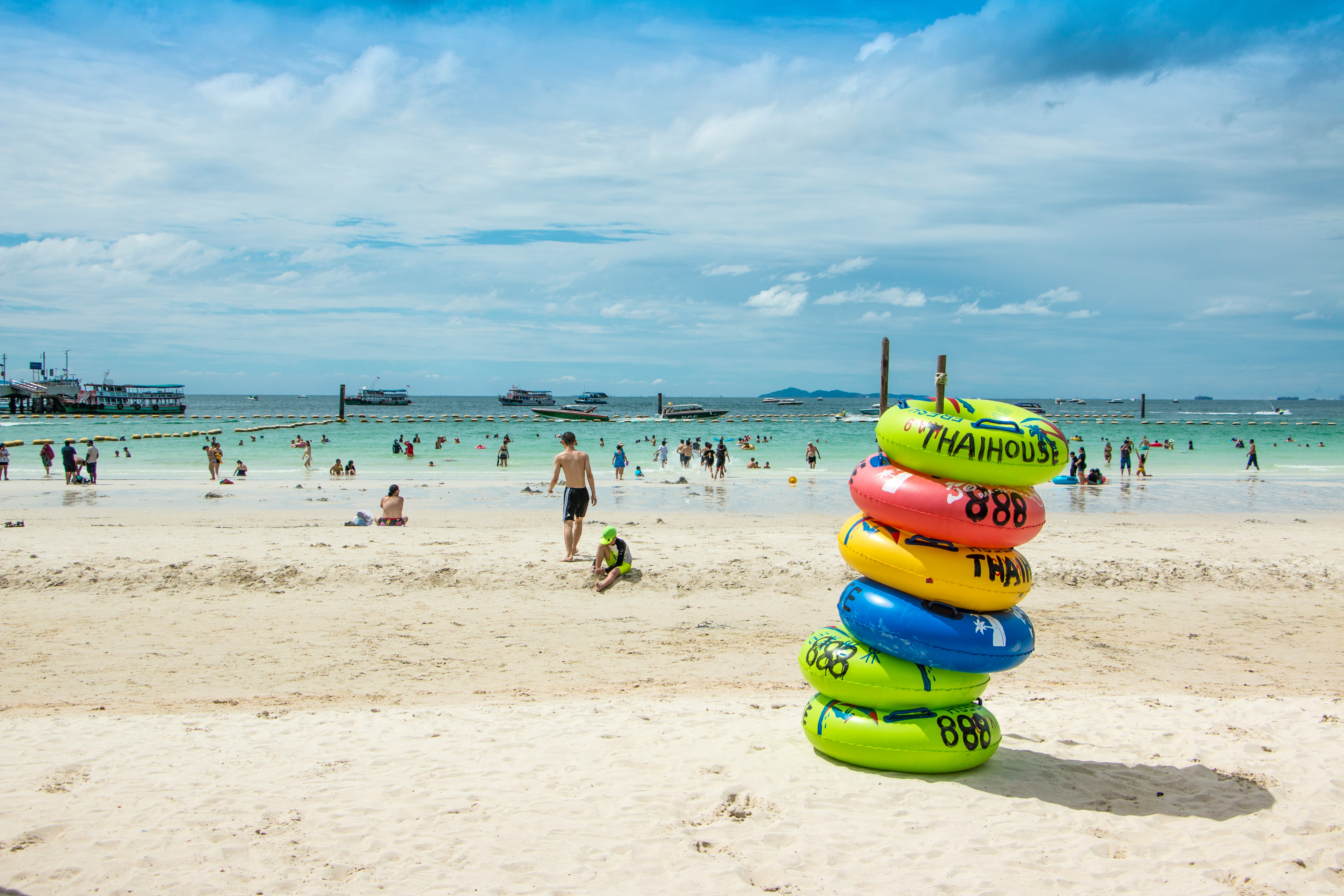 Colourful inflatable rings on Ko Larn beach with boats and sea in the background, Pattaya, Thailand