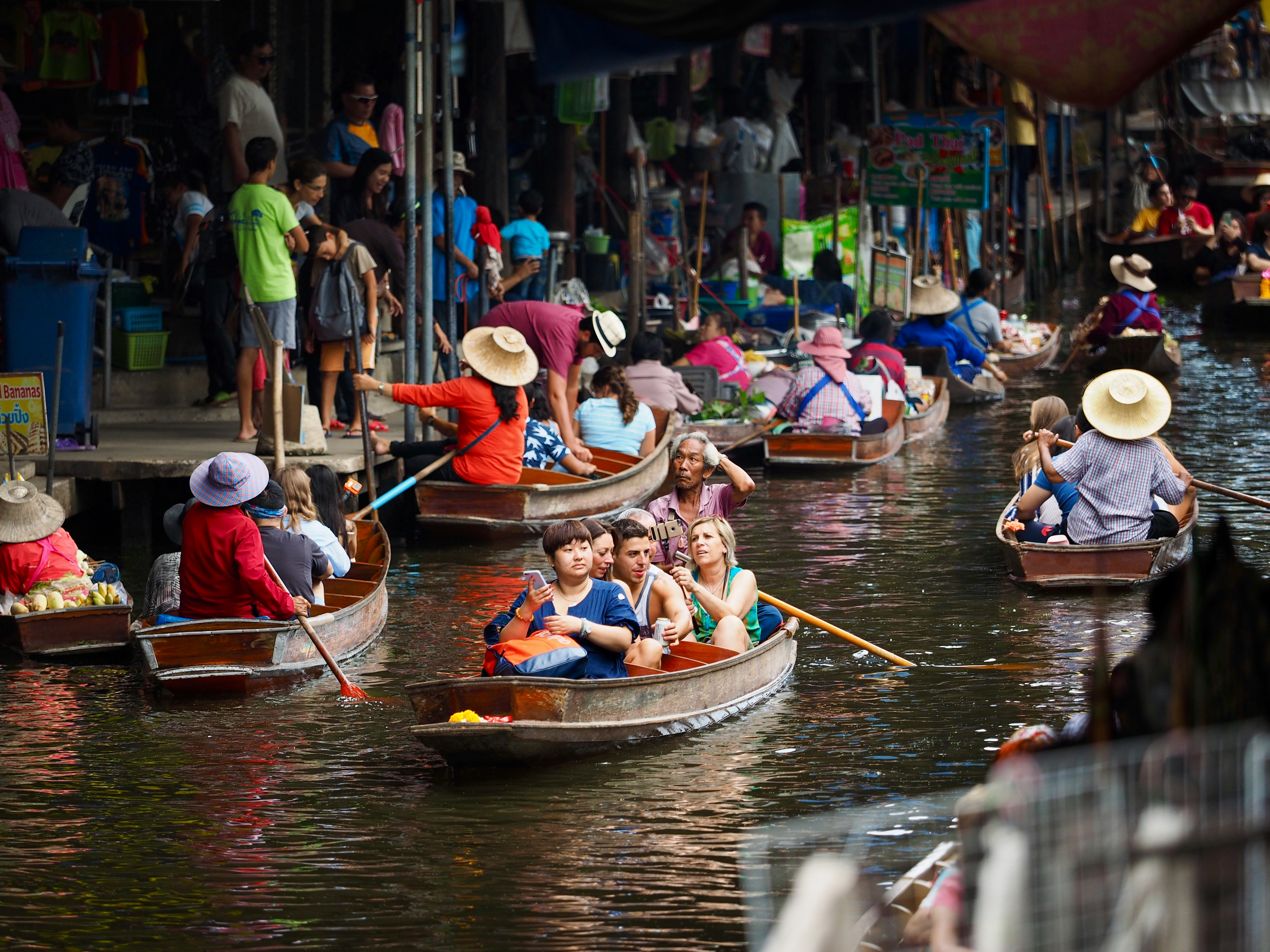 Visitors on rowing boats navigating a bustling floating market, Thailand
