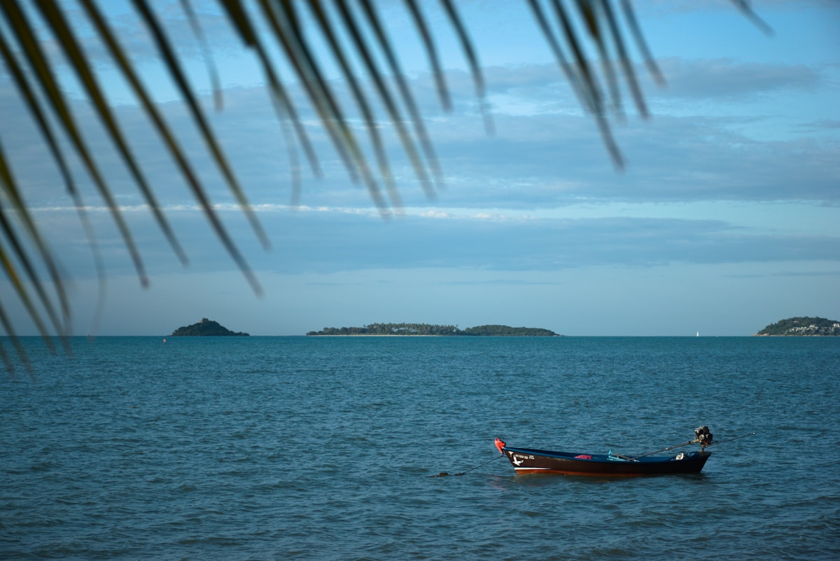 Longtail boat moored on calm turquoise water with small islands in the distance, Koh Samui, Thailand