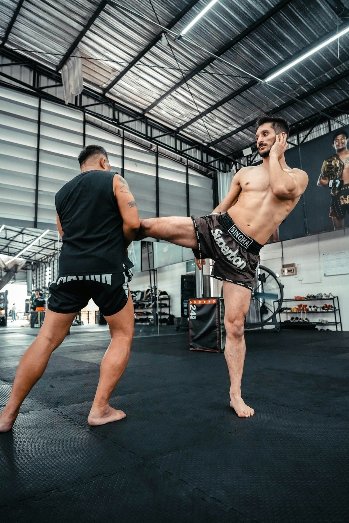Two fighters practicing Muay Thai sparring in an indoor training gym