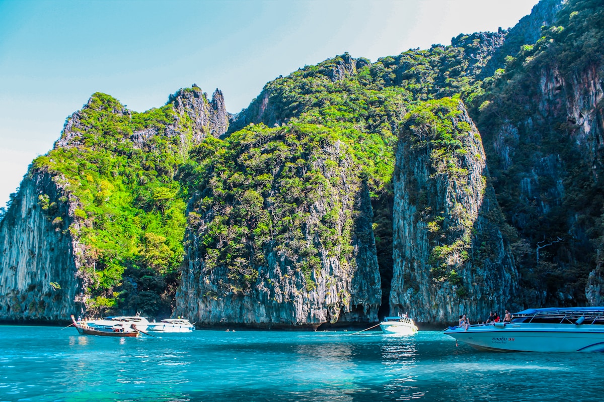 Speedboat approaching Tonsai Bay pier on Phi Phi Don island with karst cliffs behind
