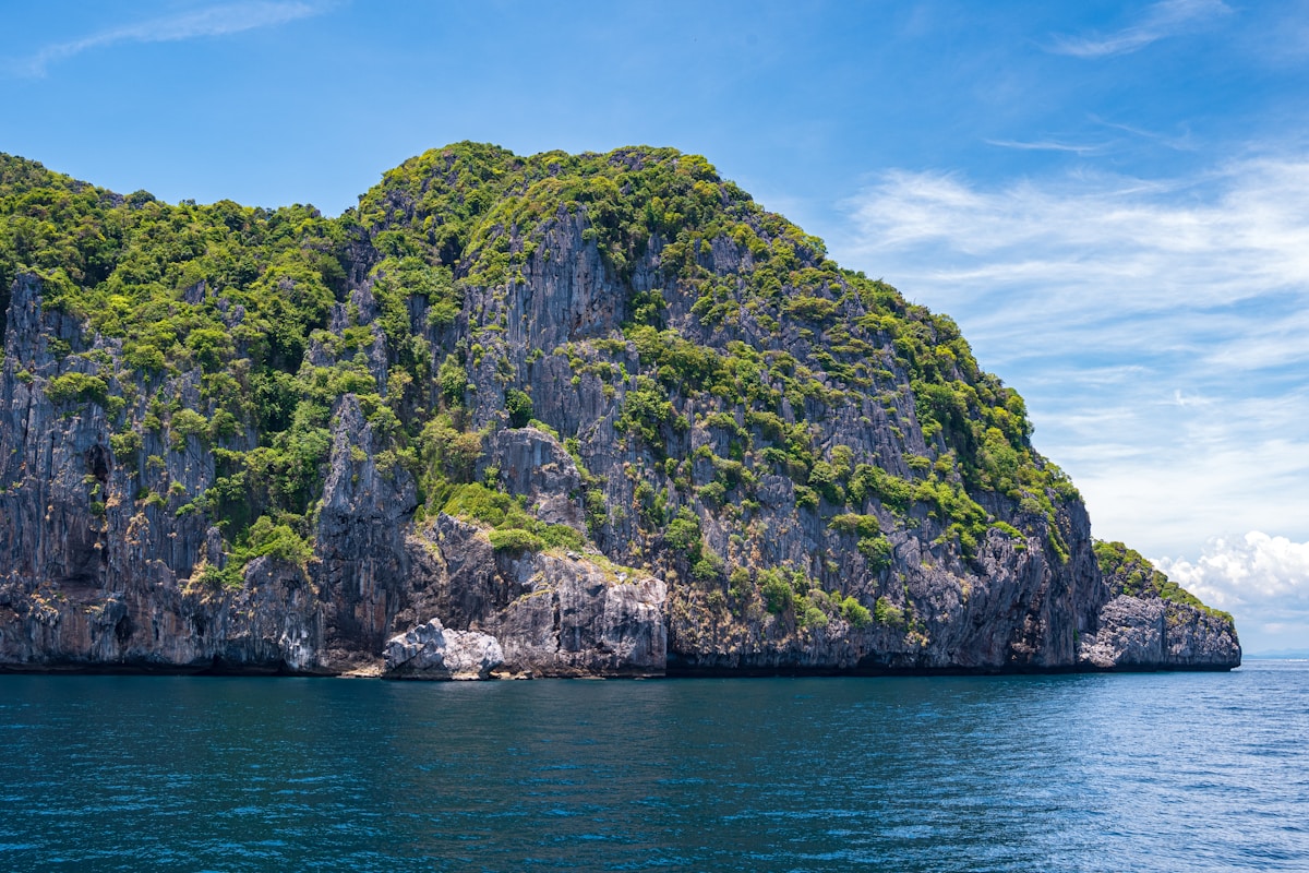Tour boats anchored in a turquoise lagoon ringed by limestone cliffs, Thailand