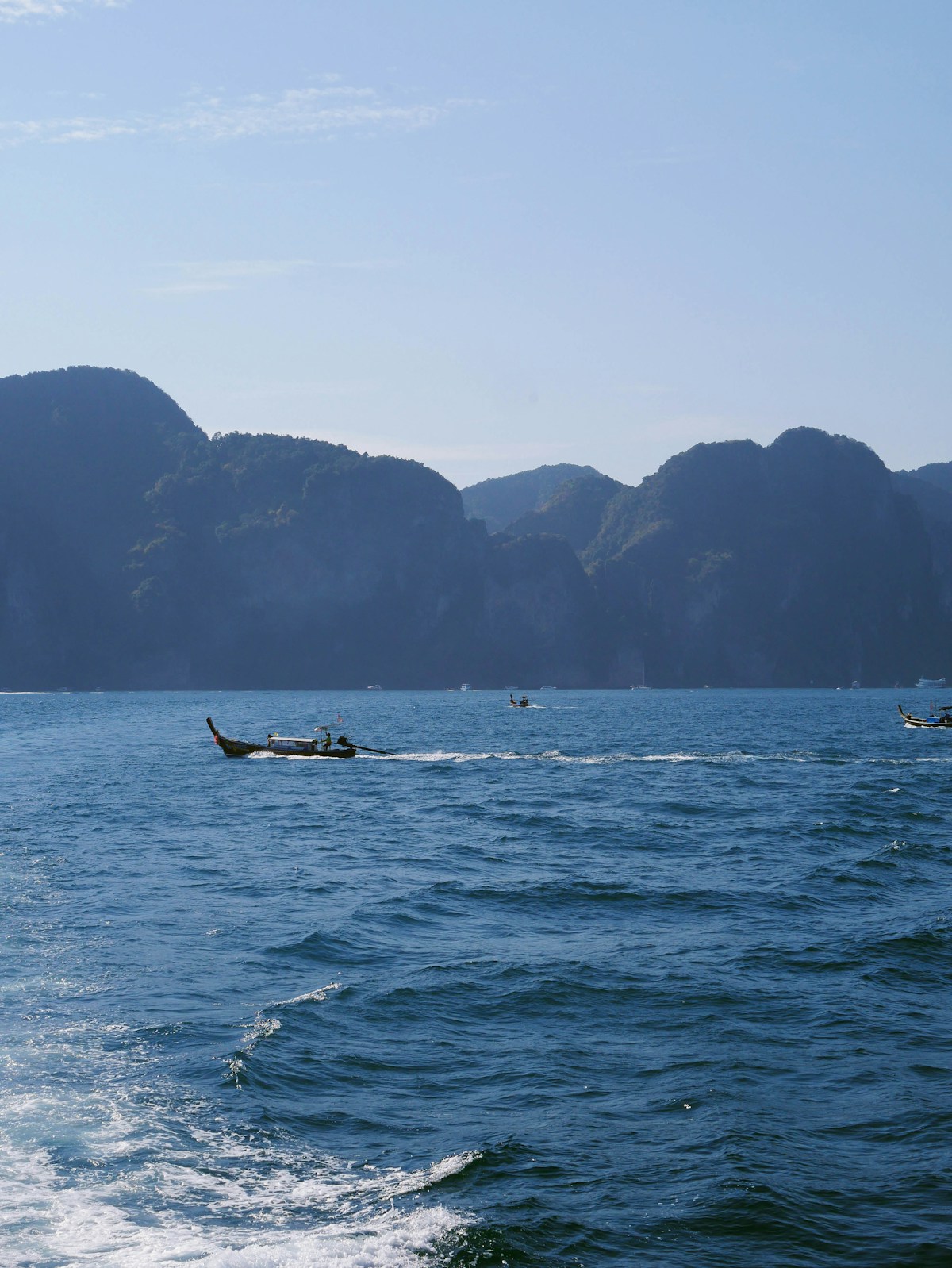Speed ferry crossing turquoise Andaman Sea toward limestone karst islands, southern Thailand