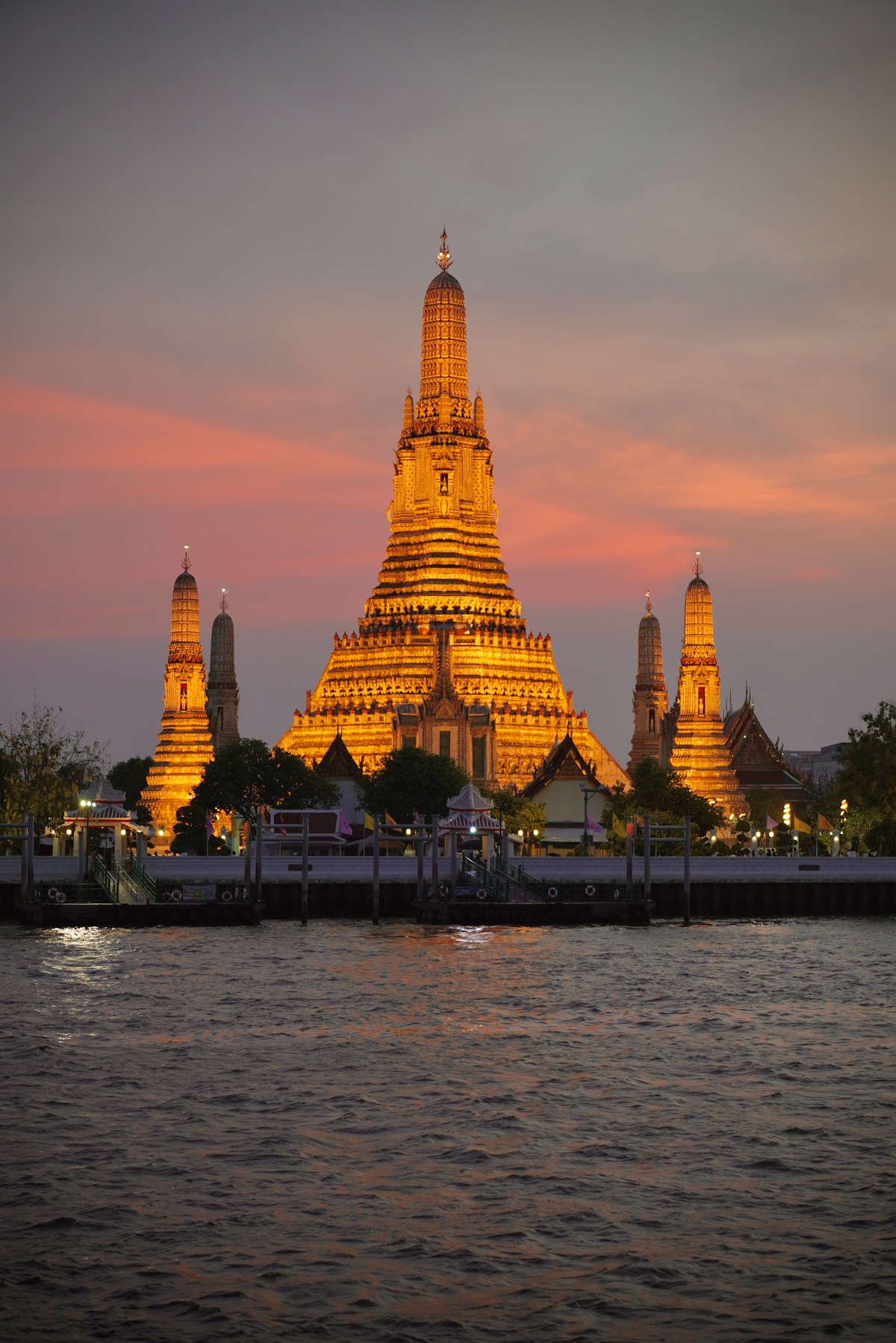 Wat Arun illuminated in gold at dusk, reflected in the Chao Phraya River, Bangkok
