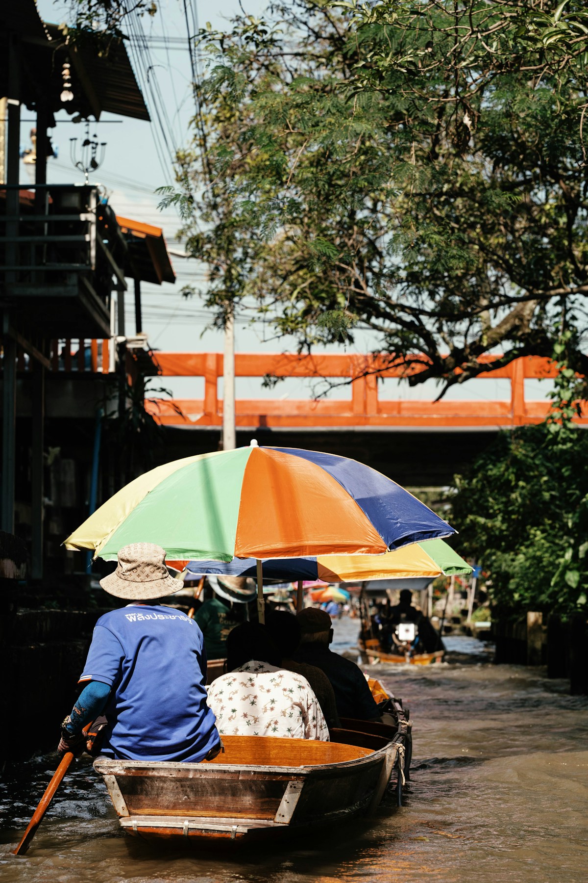 Person in small boat with colourful umbrella at a Bangkok floating market canal, Thailand
