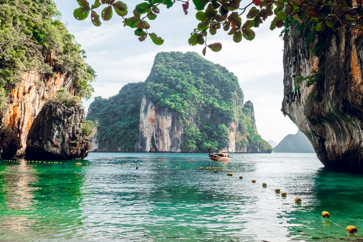 Longtail boat anchored in turquoise water between limestone karsts at Hong Island, Phang Nga, Thailand