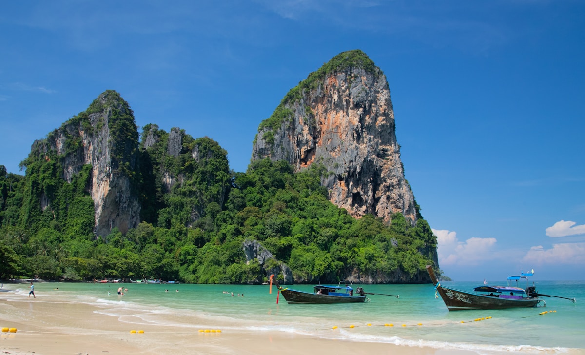 Longtail boats moored on turquoise water at Railay Beach with limestone karst