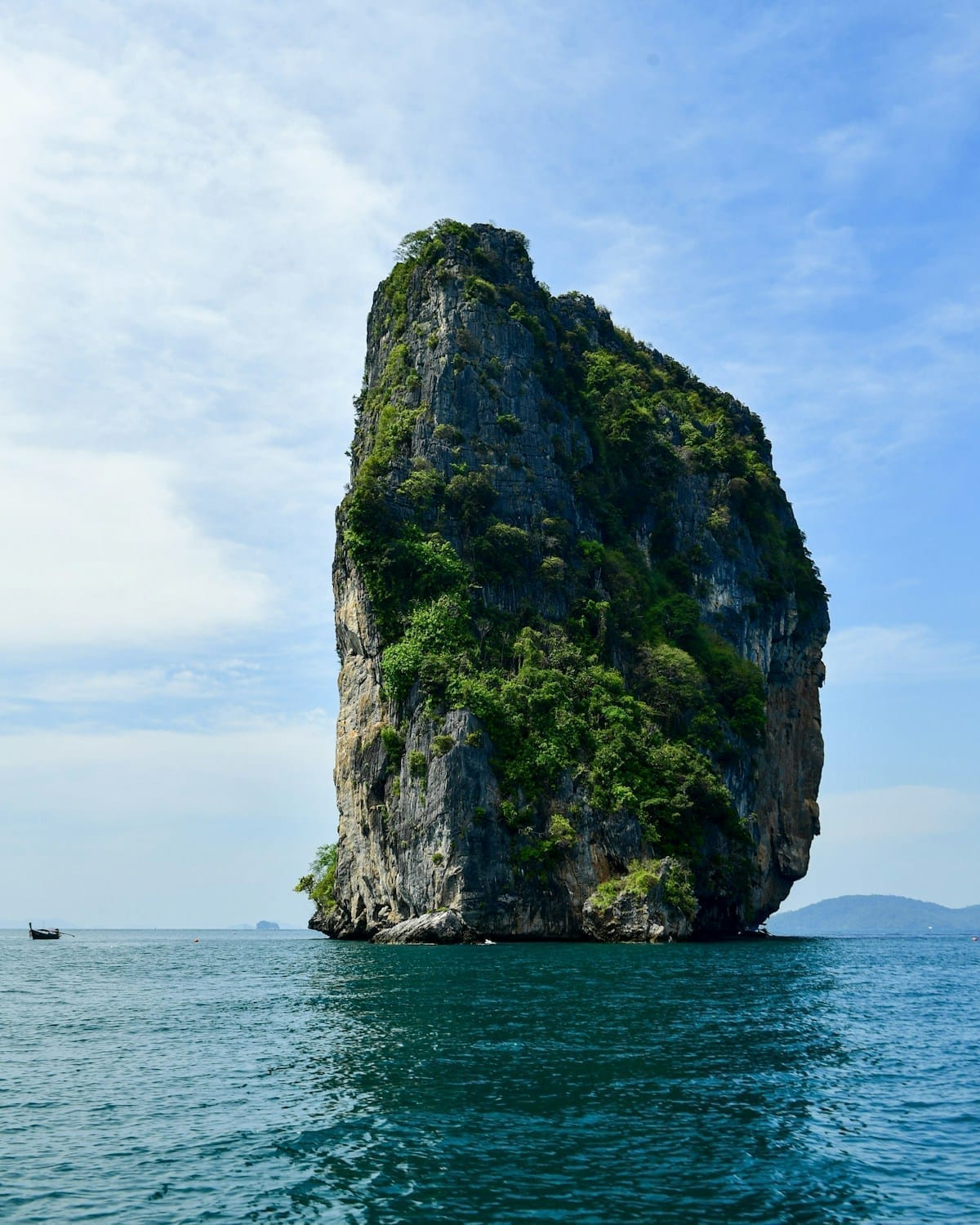 Rock climber ascending limestone cliff face above Railay Beach, Krabi