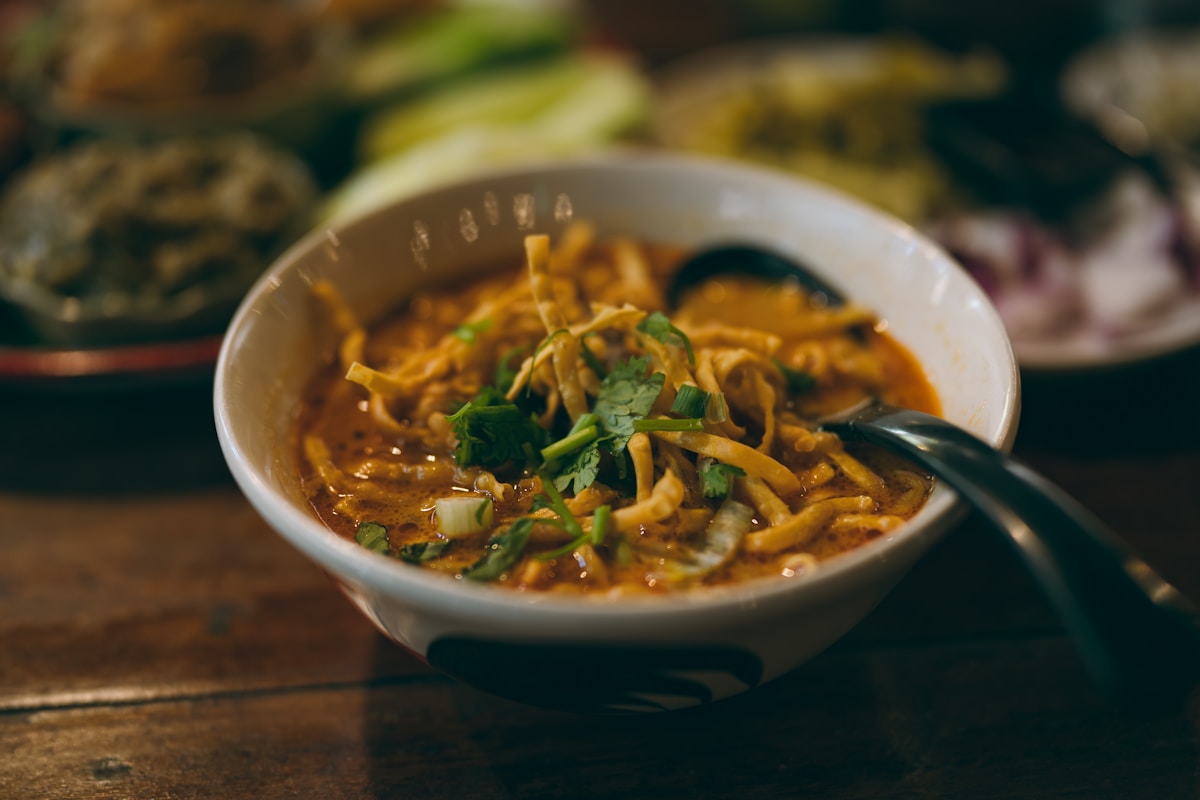 Bowl of khao soi curry noodles with crispy noodles and lime, northern Thailand