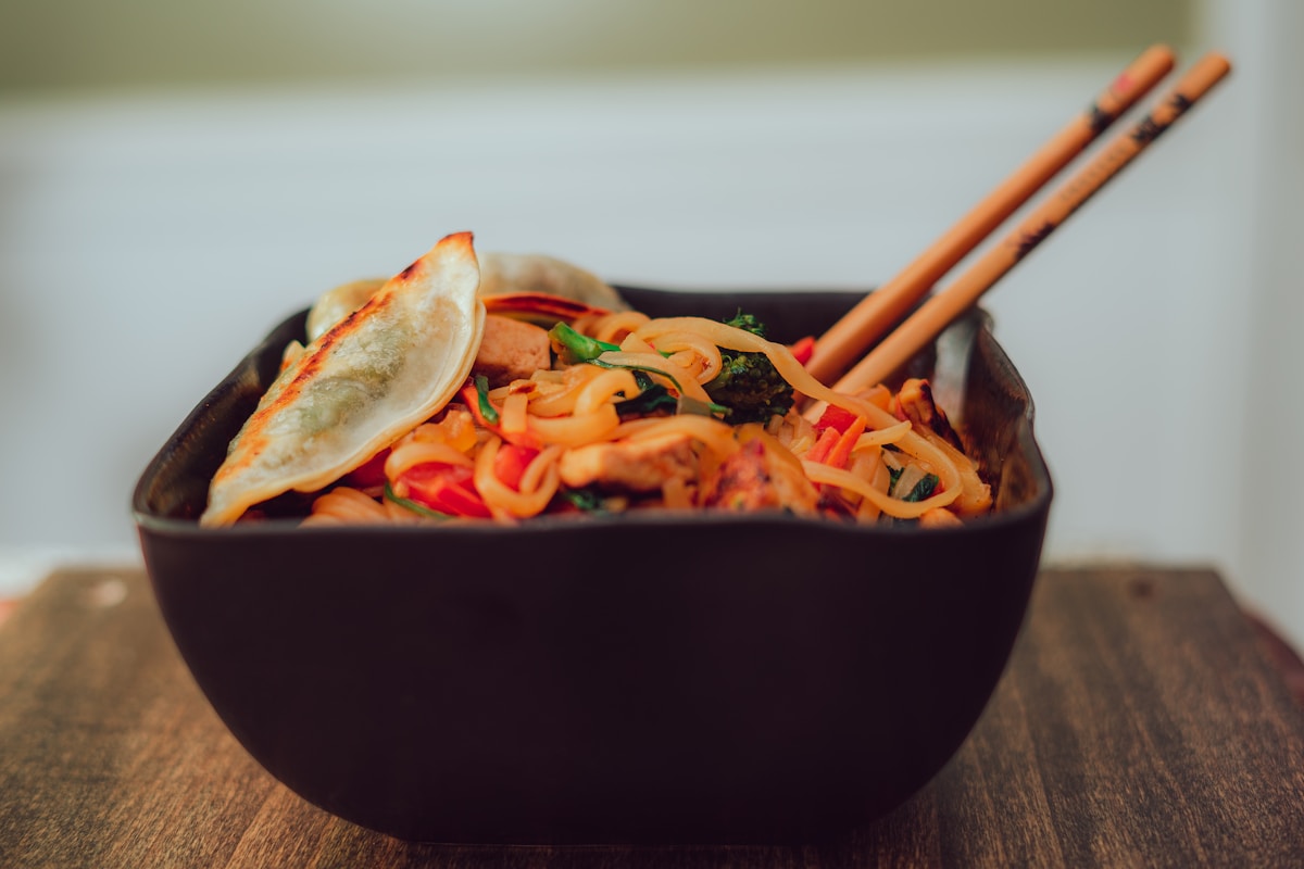 Asian noodles in a dark bowl with chopsticks — Thai cuisine
