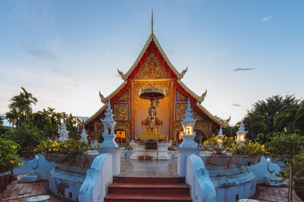Vergoldeter Viharn mit rotem Dach des Wat Phra Singh in Chiang Mai unter blauem Abendhimmel