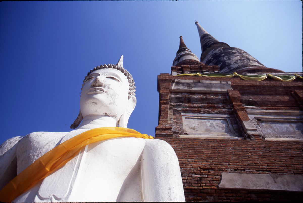 Weiße Buddha-Statue neben einem Backstein-Chedi im Wat Yai Chai Mongkhon, Ayutthaya