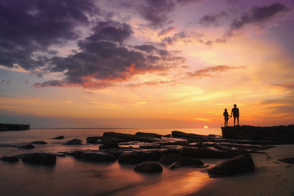 Deux silhouettes sur les rochers au coucher du soleil à Ko Kut, une île tranquille pour les couples