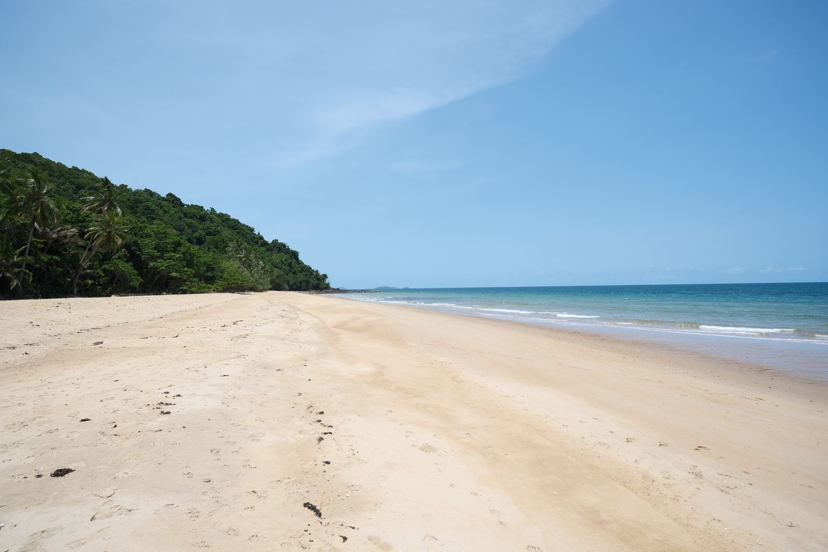 Une longue plage tranquille bordée de forêt sur la côte de Koh Lanta