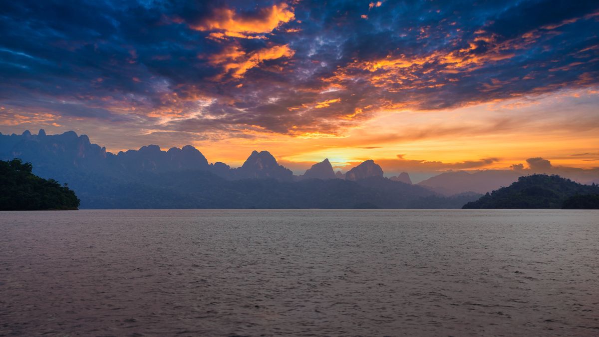 Coucher de soleil sur un lac entouré de calcaire dans la région de Khao Sok, province de Surat Thani