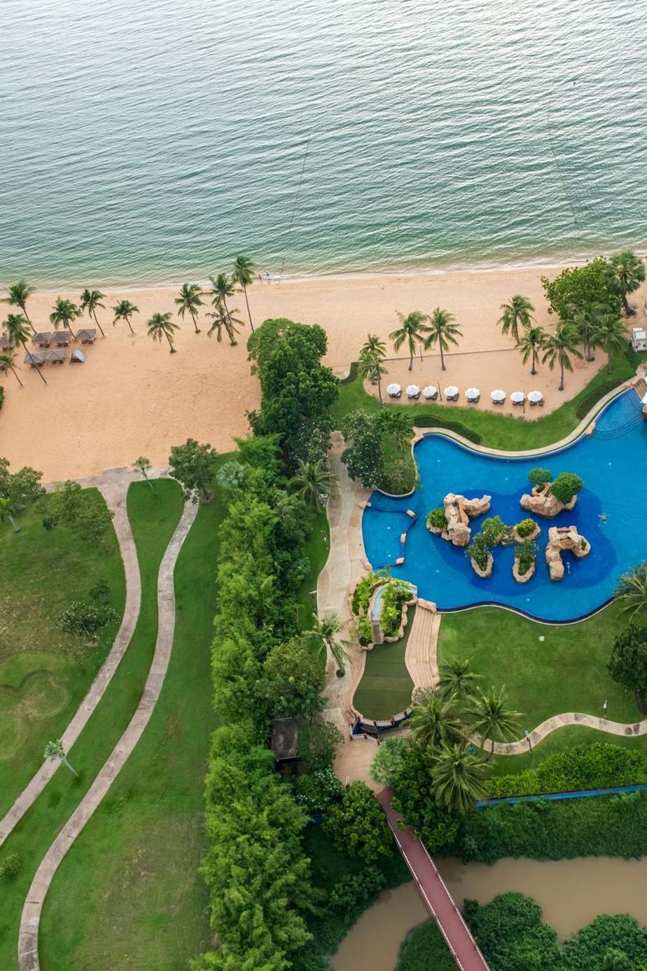 Luftaufnahme eines Resorts mit Pool und Palmen am Strand in Chon Buri