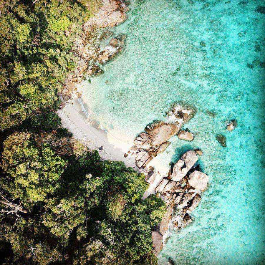 Vue aérienne d'une petite plage avec blocs de granit et eau turquoise limpide en mer d'Andaman