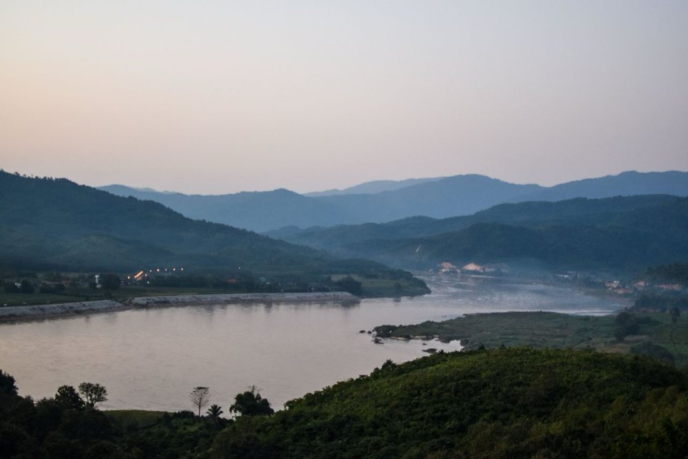 Der Mekong in der Abenddämmerung zwischen bewaldeten Hügeln nahe dem Goldenen Dreieck in der Provinz Chiang Rai