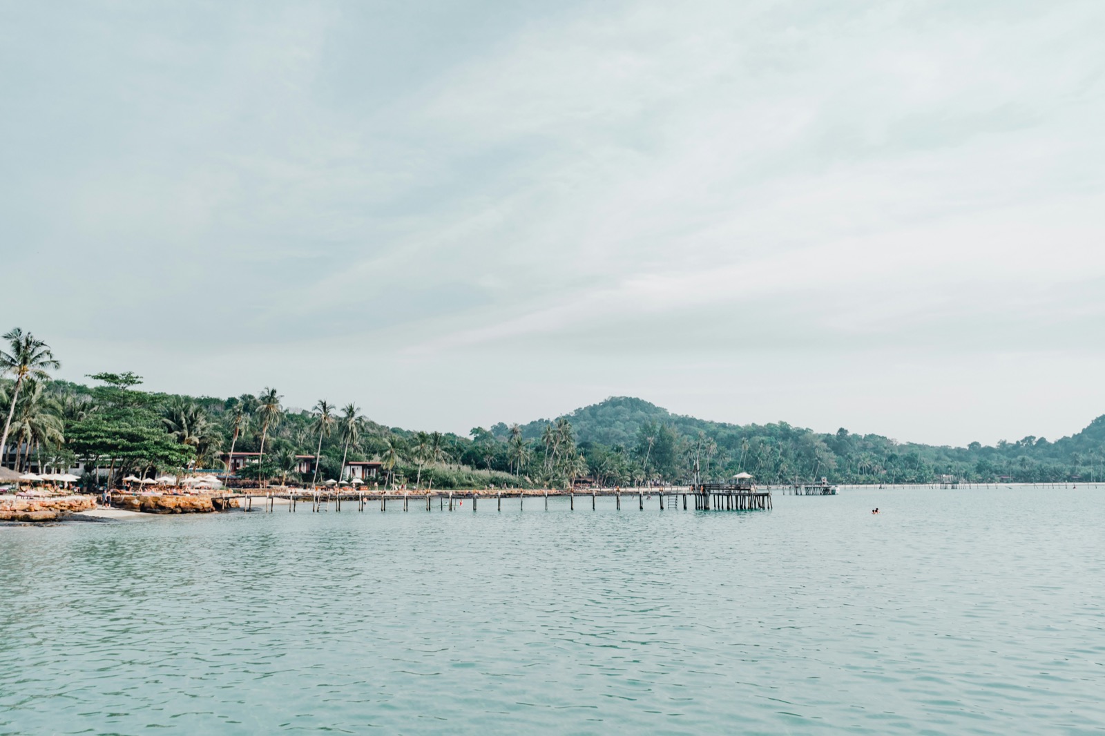 Beach resort with wooden pier, palm trees and forested hills, Ko Kut, Trat province, Thailand