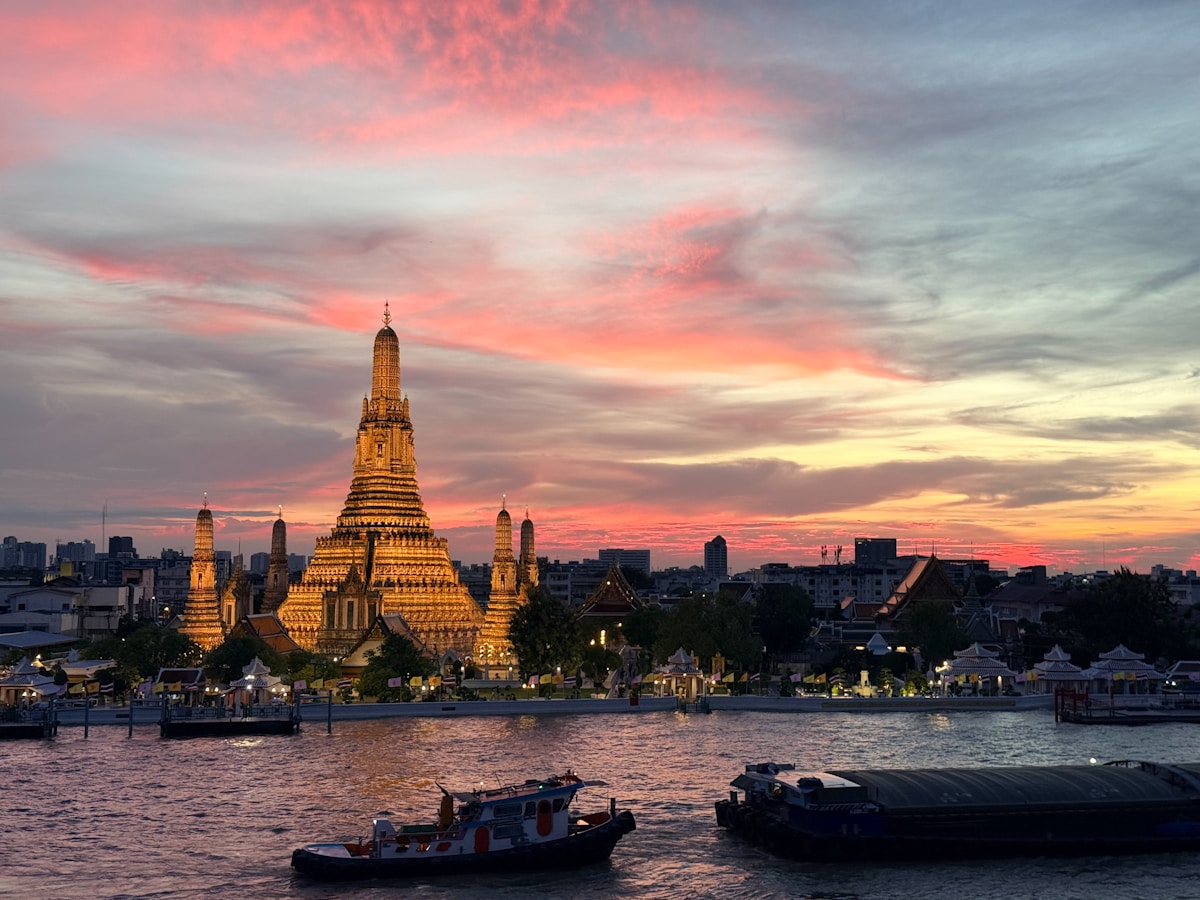 Wat Arun temple illuminated at sunset on the Chao Phraya River, Bangkok