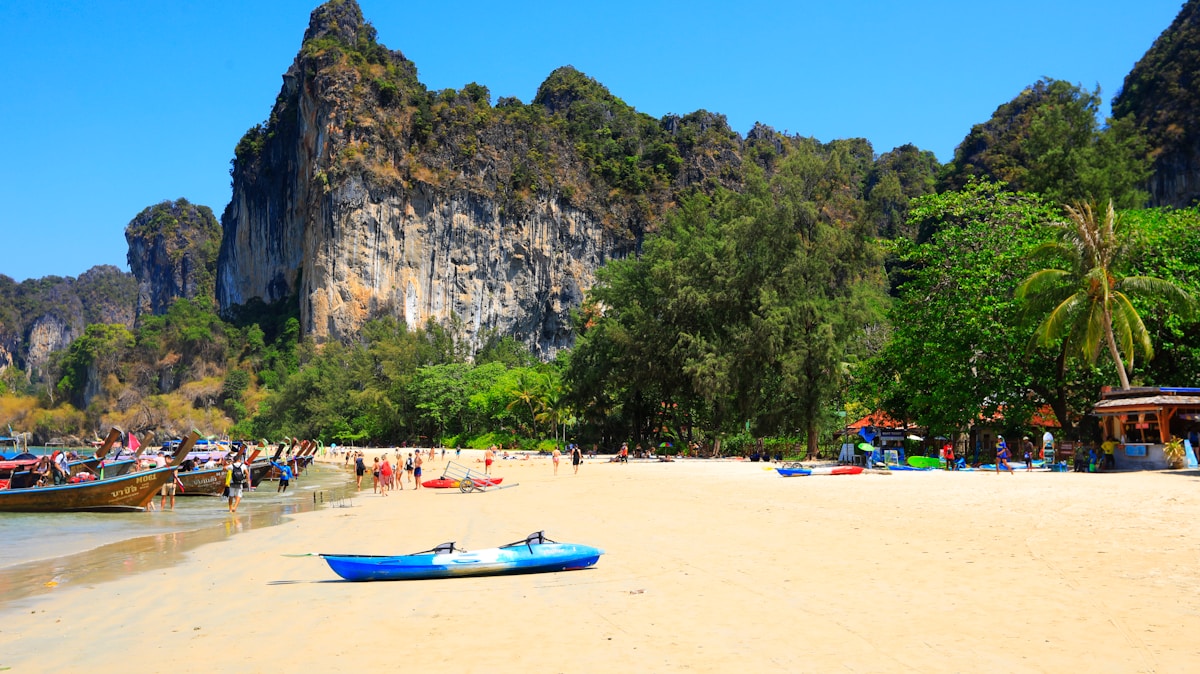 Kayaks and longtail boats on Railay Beach with limestone cliffs, Krabi