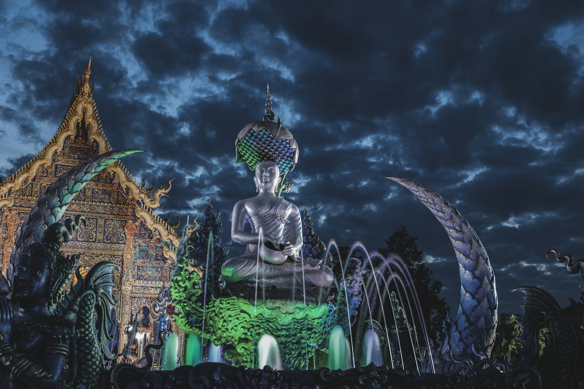 Blue Temple (Wat Rong Suea Ten) Buddha statue illuminated at night, Chiang Rai, Thailand