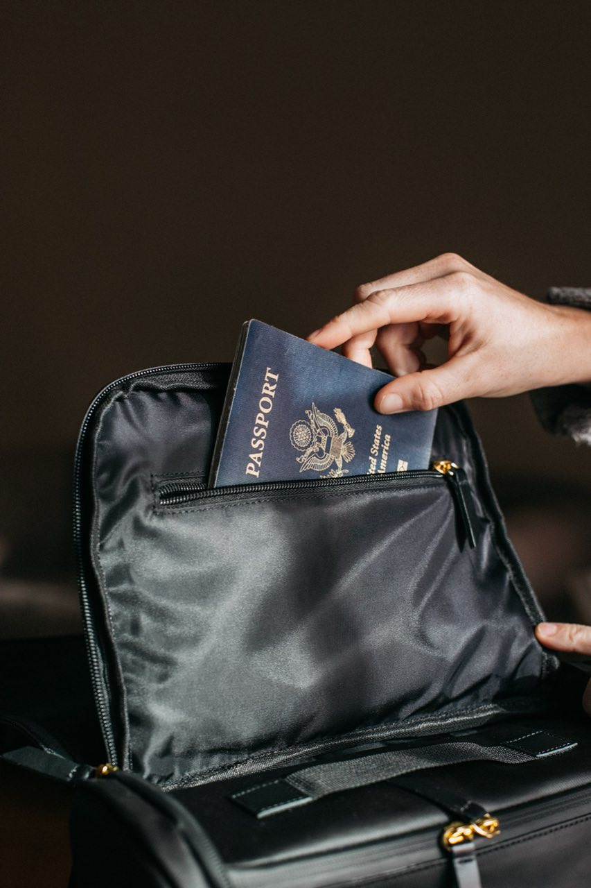 Hand placing a passport into a travel bag