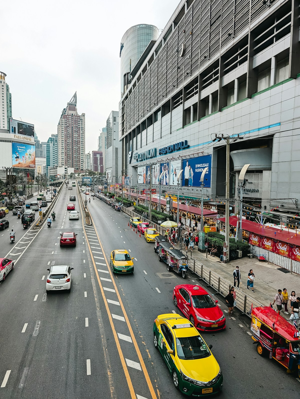City street scene in Bangkok with yellow taxis and modern high-rise buildings