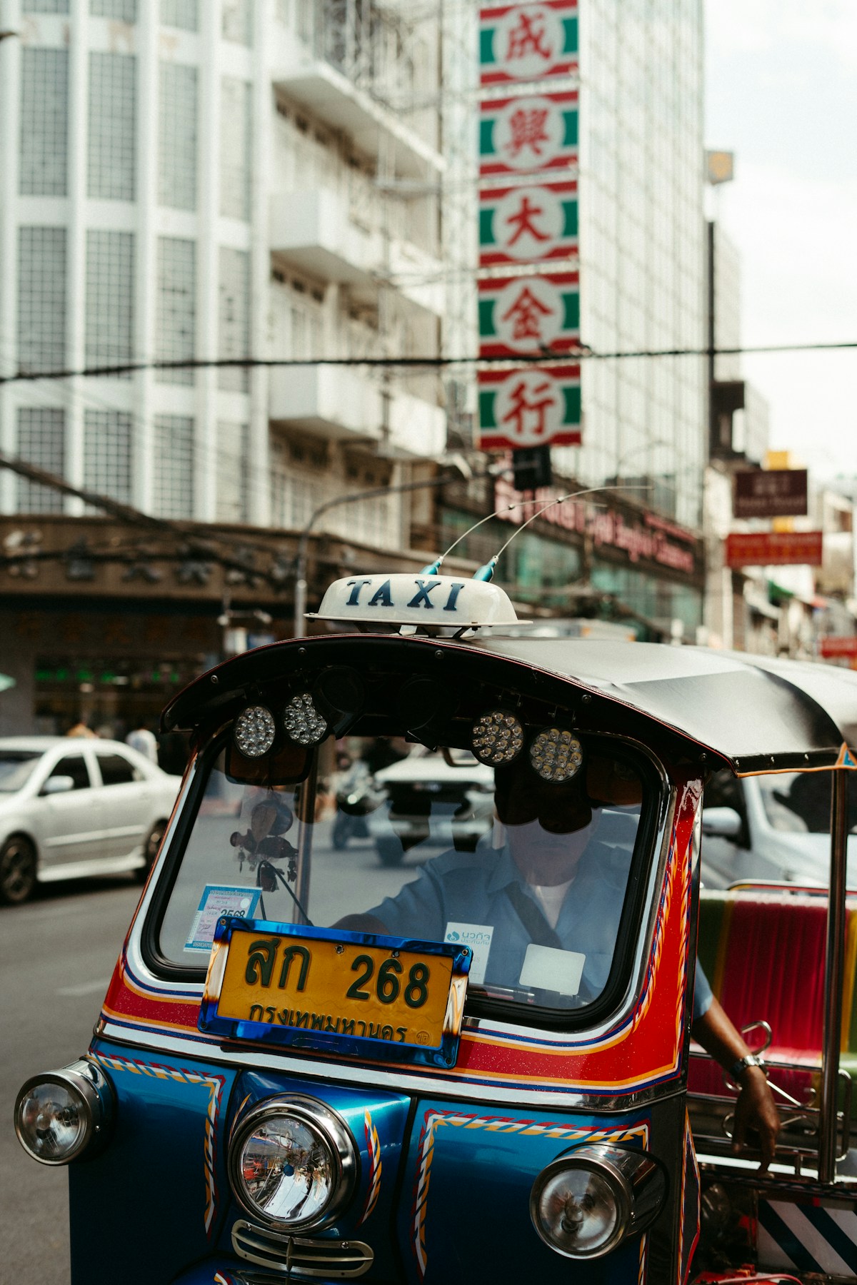 A tuk-tuk taxi driving on a Bangkok street in Chinatown