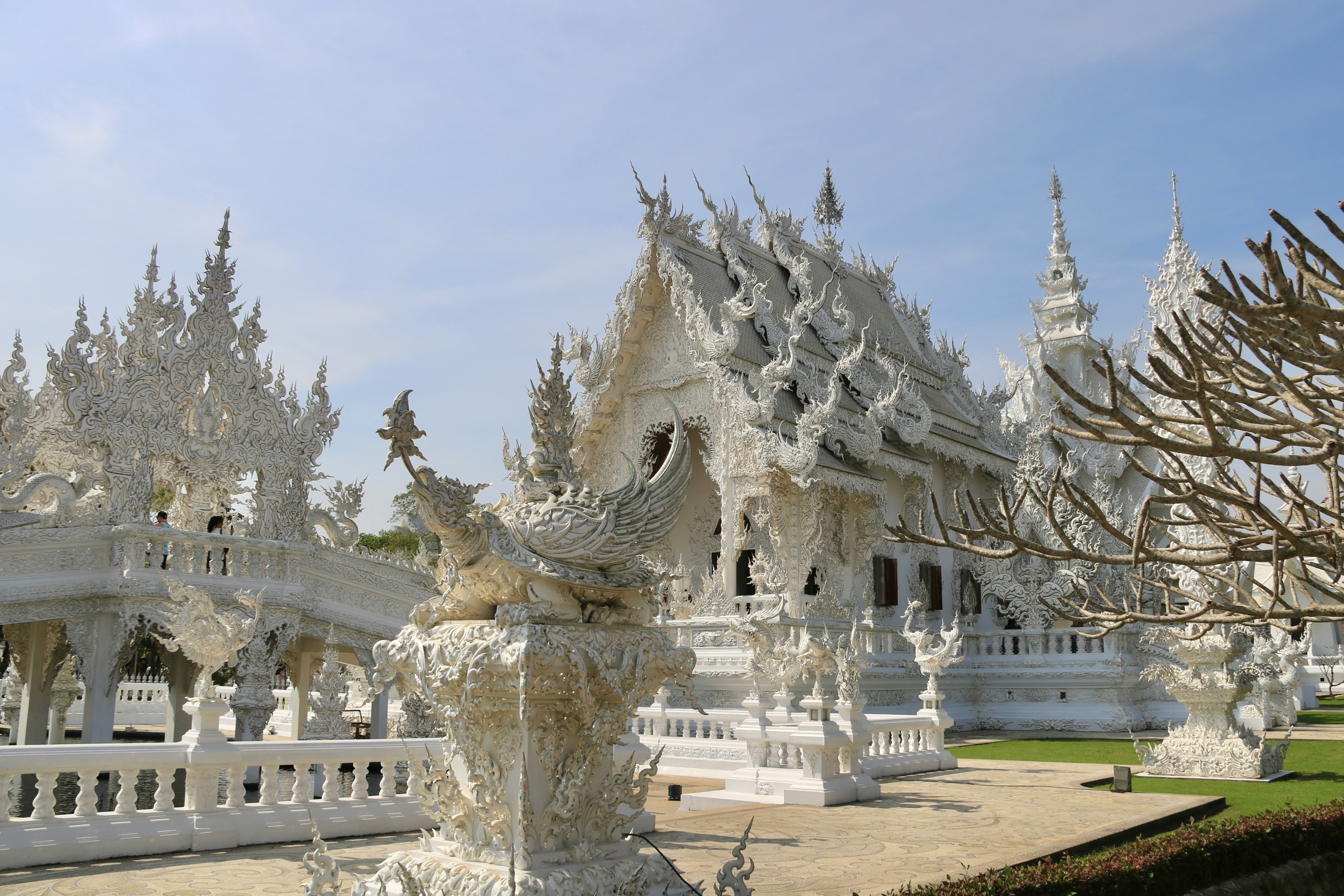 The intricate white facade and ornate carvings of Wat Rong Khun (White Temple) under blue sky in Chiang Rai province, Thailand