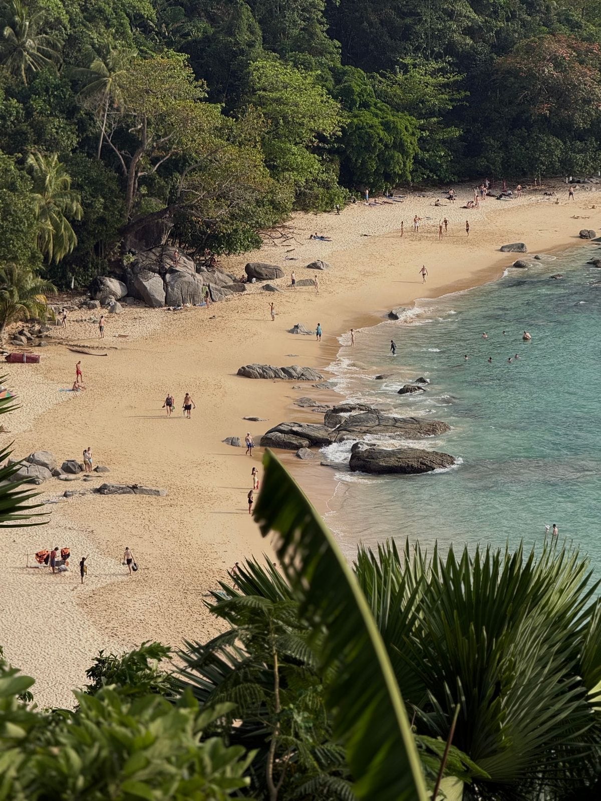 Tropical beach with turquoise water and jungle-covered hills in Phuket, Southern Thailand