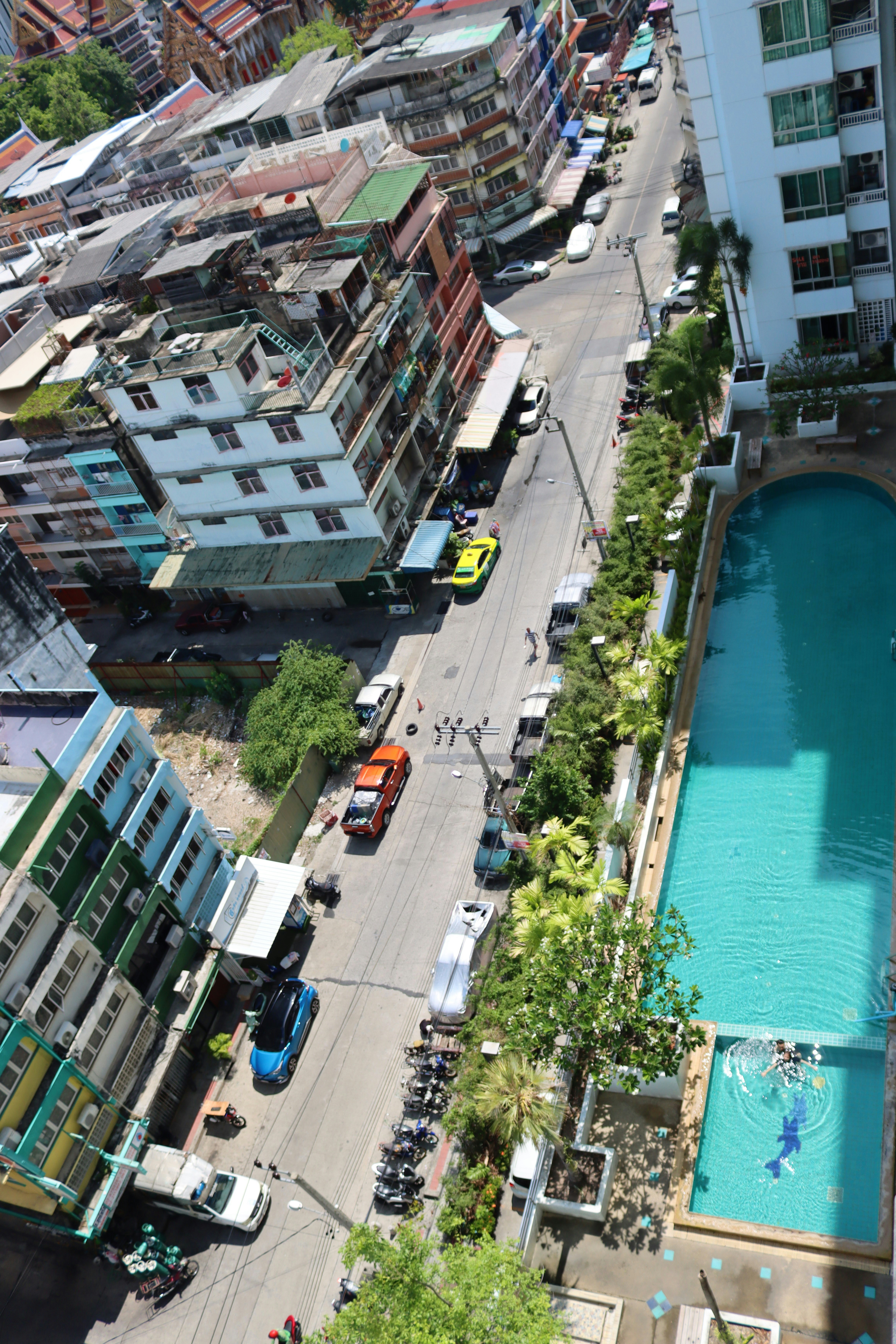 Aerial view of Bangkok street with a rooftop swimming pool alongside a mid-rise apartment building