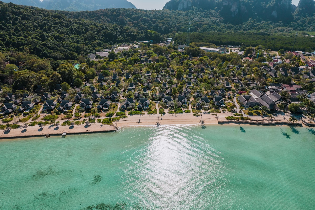 Aerial view of beach bungalows and resort area surrounded by lush jungle and limestone karst cliffs, Andaman coast, Thailand