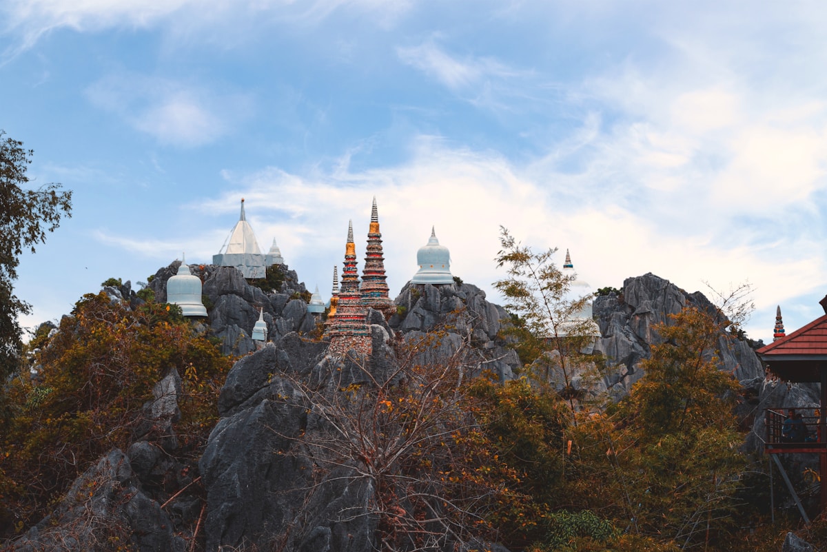 Buddhist temple spires and white chedis rising from a rocky hilltop, northern Thailand