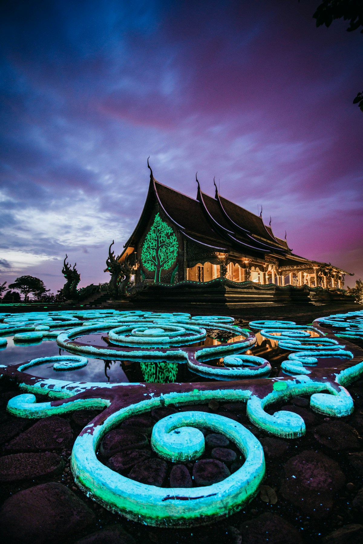 Illuminated temple with glowing green lotus pond at night, Ubon Ratchathani, Thailand